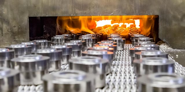 Powdered metal parts being sintered in oven